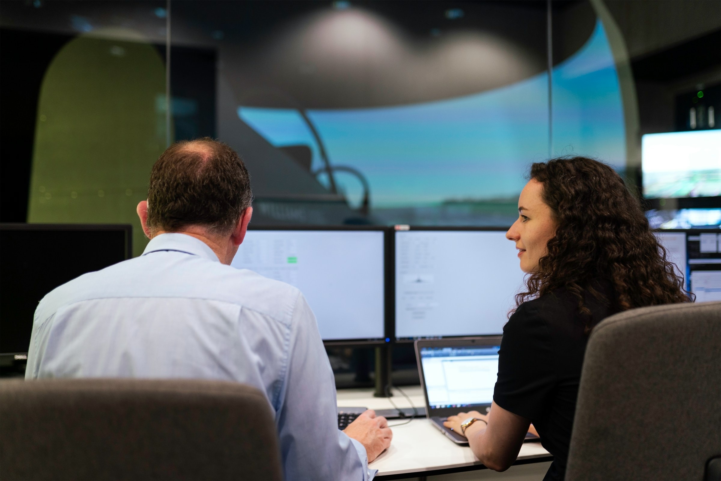 Two engineers watching system monitors in an operations room