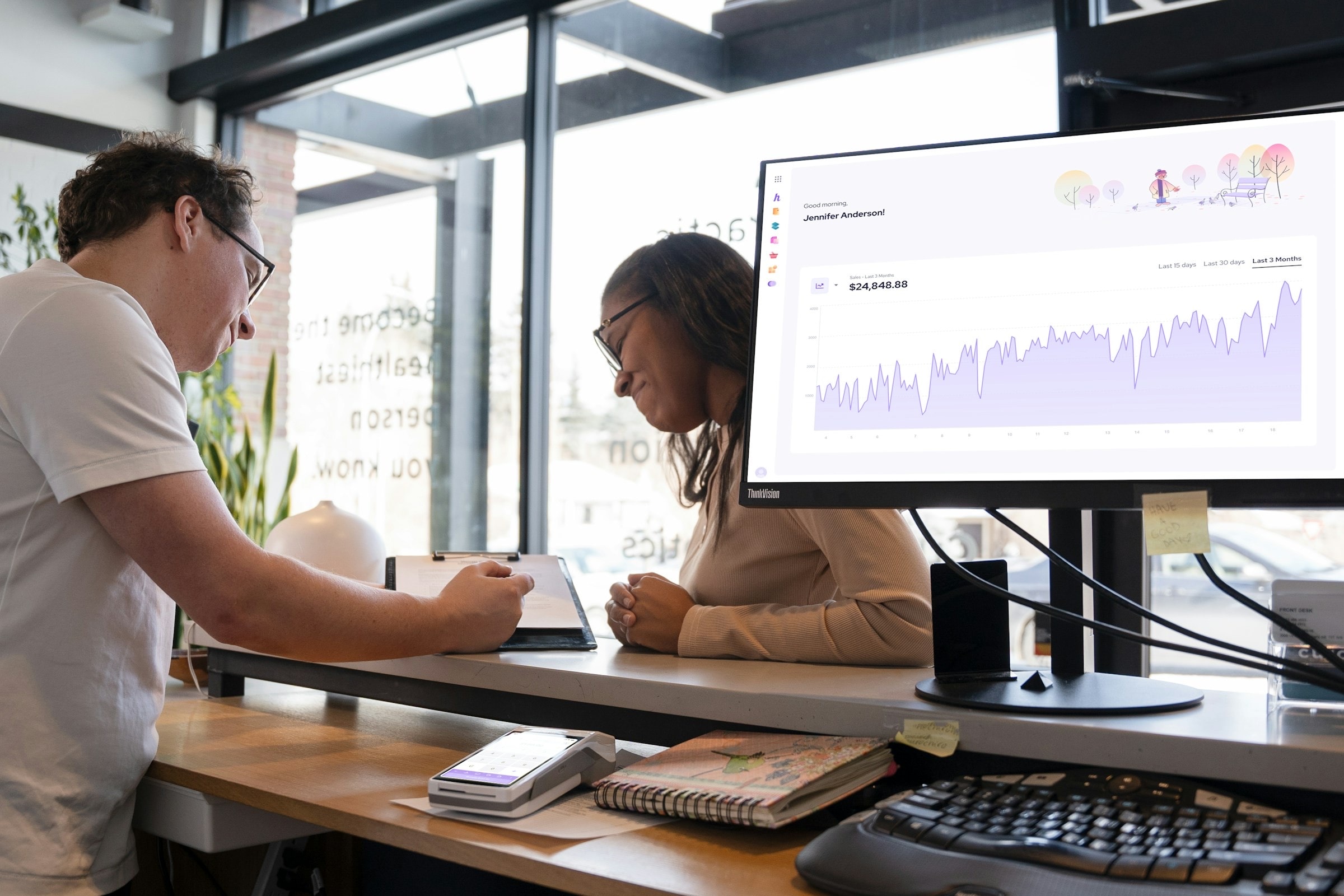 Two colleagues reviewing a sales chart on a desktop monitor