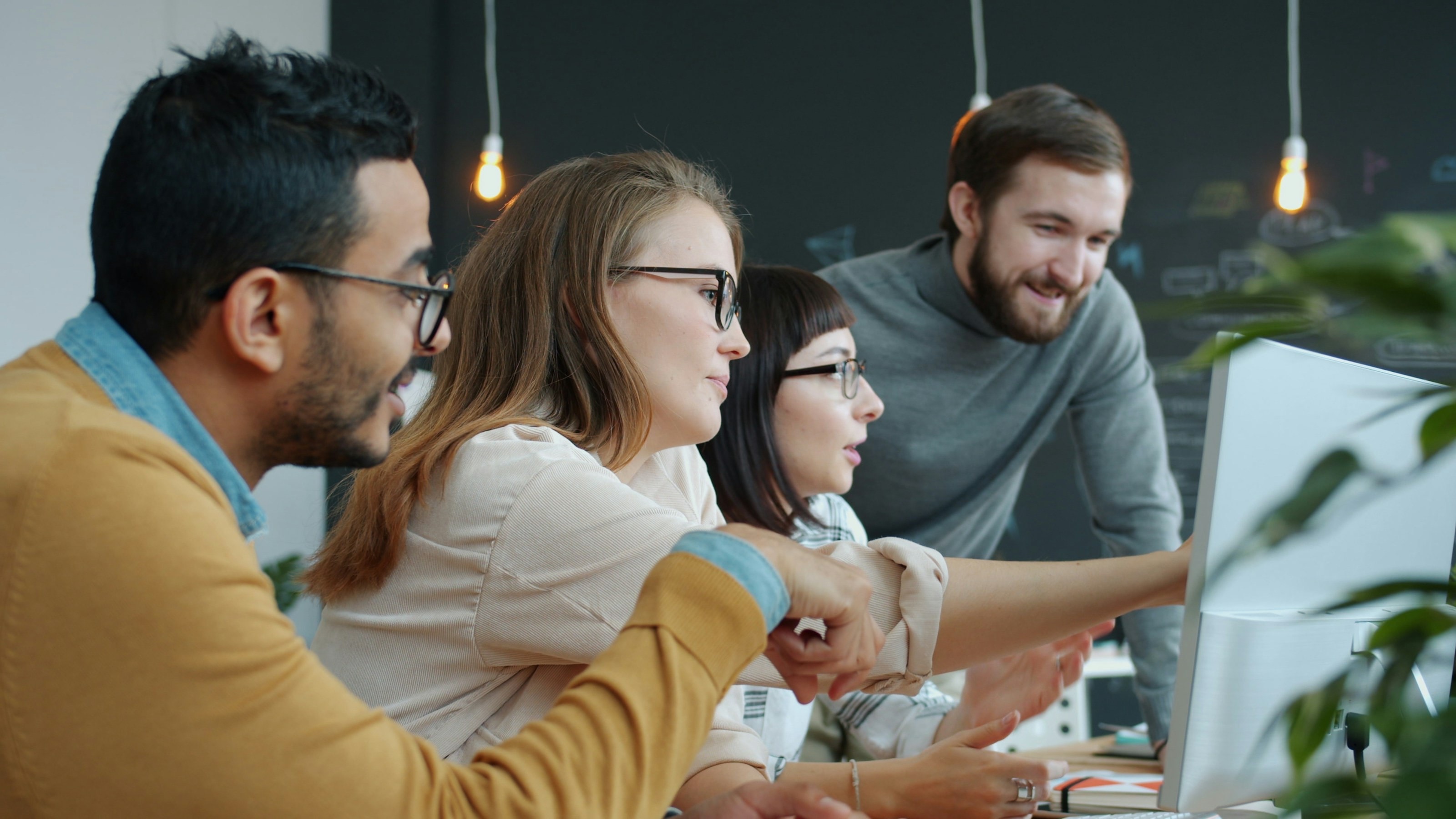 A team gathered around a monitor, working through a problem together