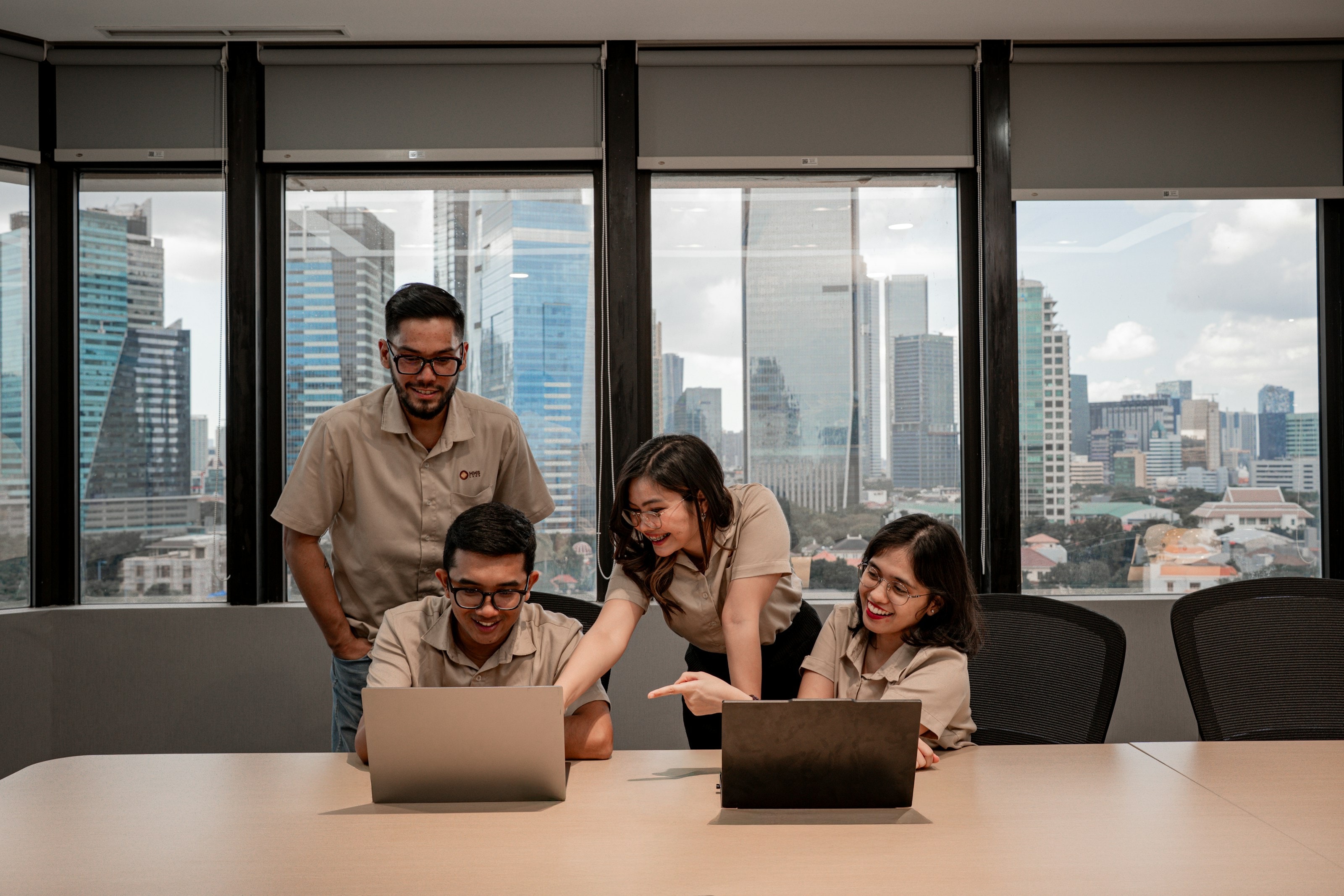 A team working together on laptops in an office overlooking the city